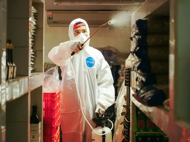 Técnico de Clean Control con traje blanco aplicando tratamiento en una bodega