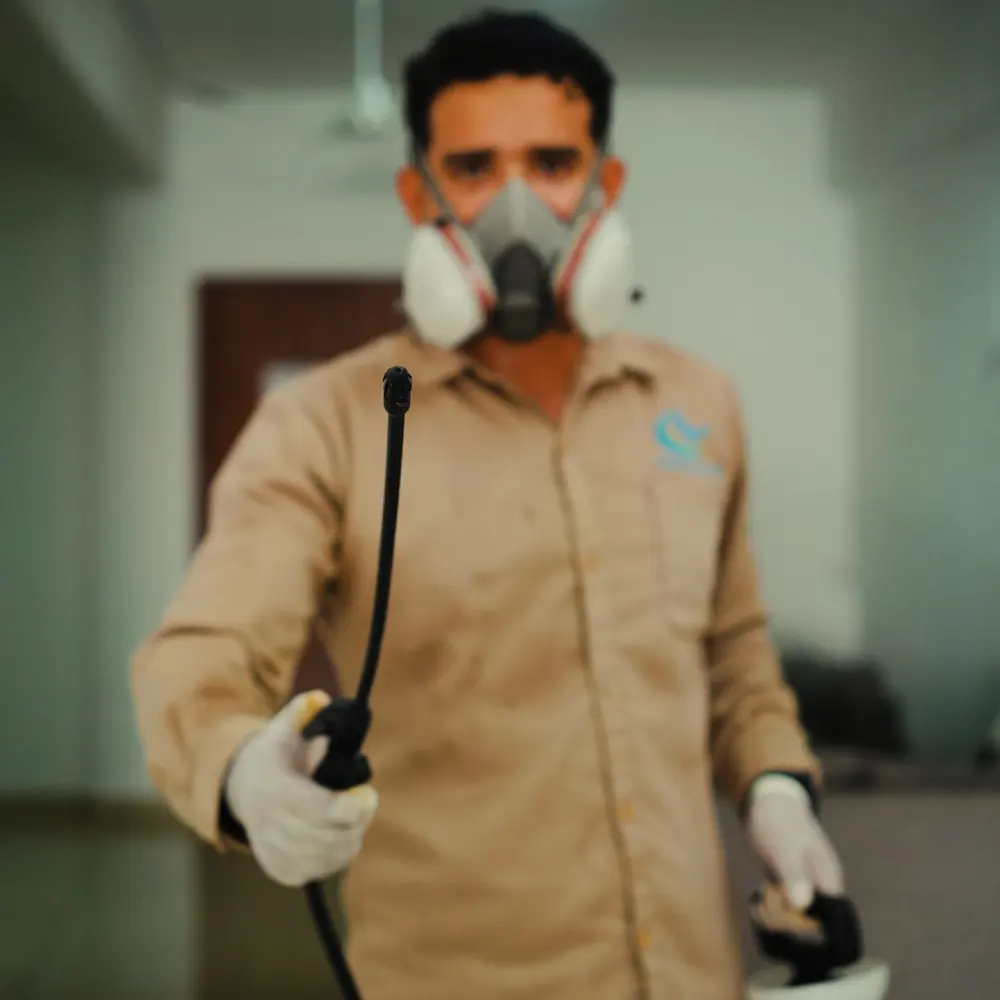 Técnico de Clean Control con mascarilla y uniforme sosteniendo el equipo de aplicación